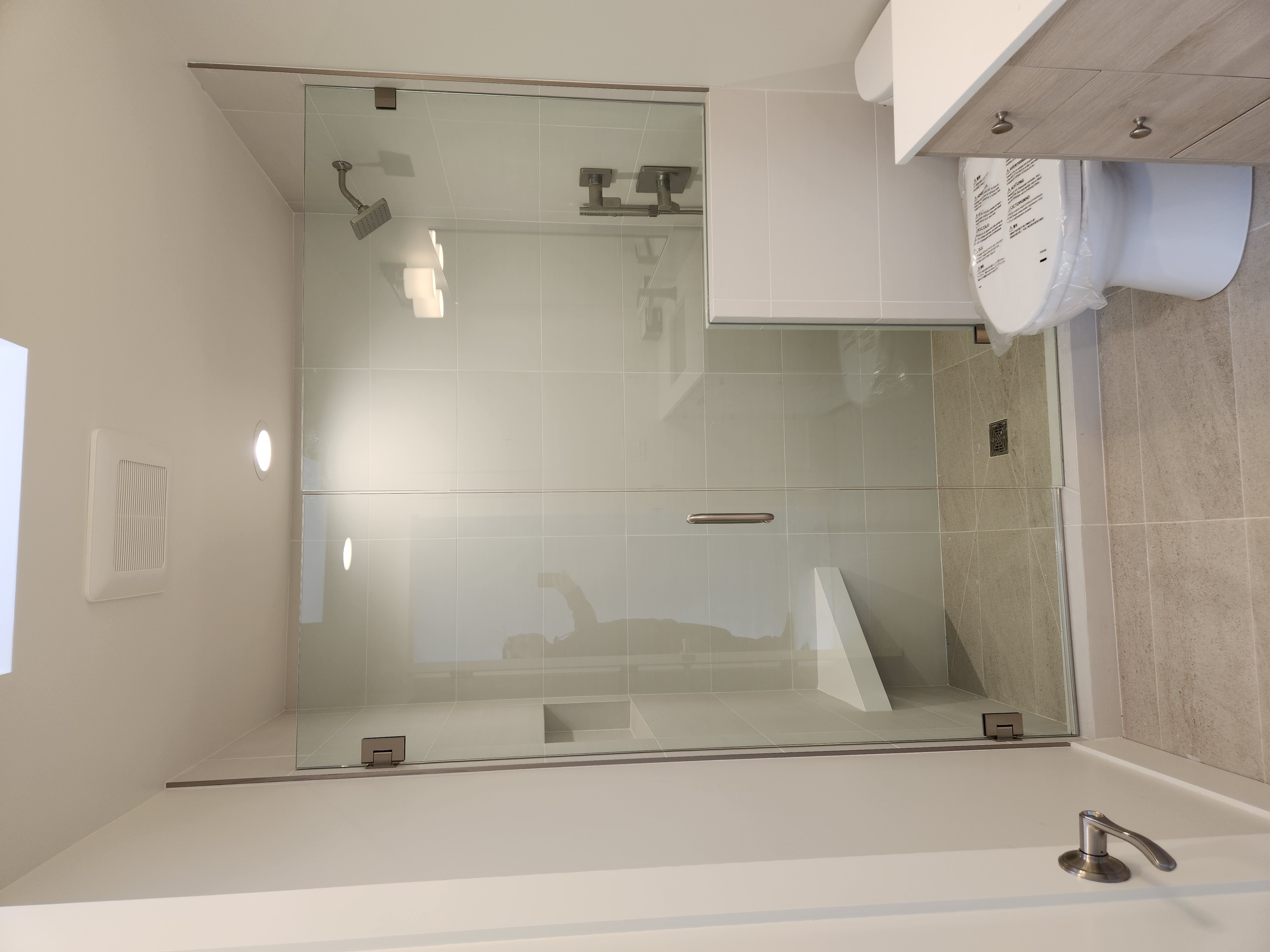 Completed bathroom remodel with glass-enclosed shower and tub